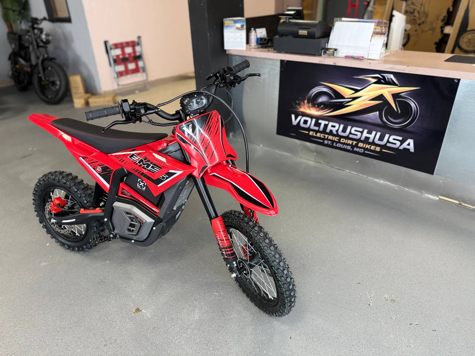 Red electric dirt bike displayed near the VoltRush USA counter