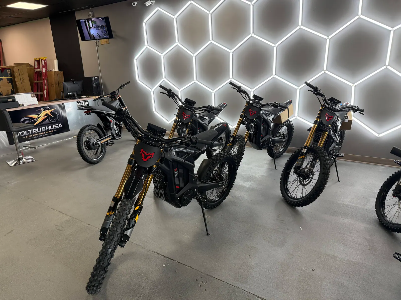 Electric dirt bike models displayed against the illuminated VoltRush USA showroom wall